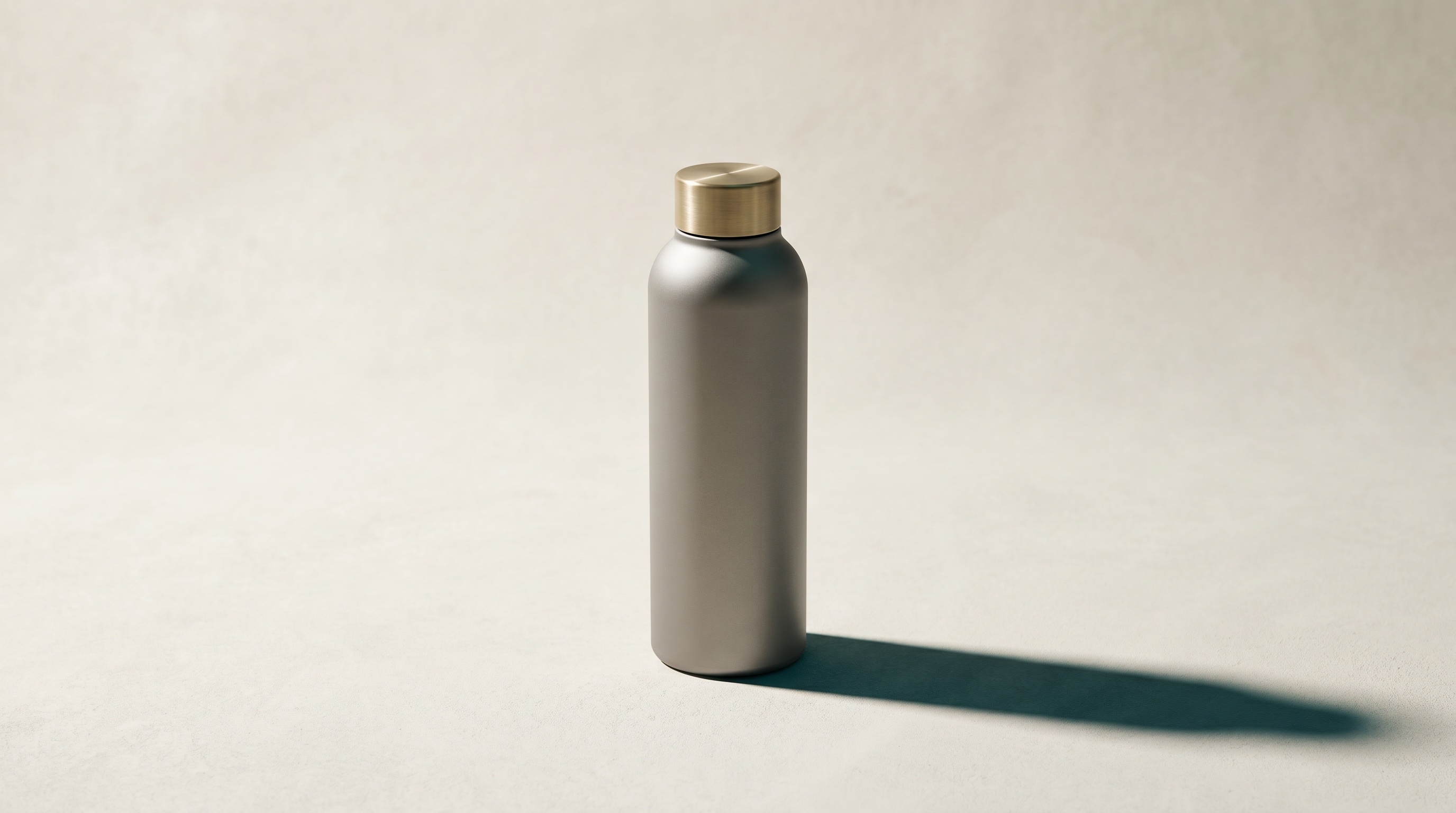 Aurea Bottle Co — editorial hero of a premium insulated metal bottle on a bone backdrop, brushed-gold lid, soft directional light, deep crisp shadow